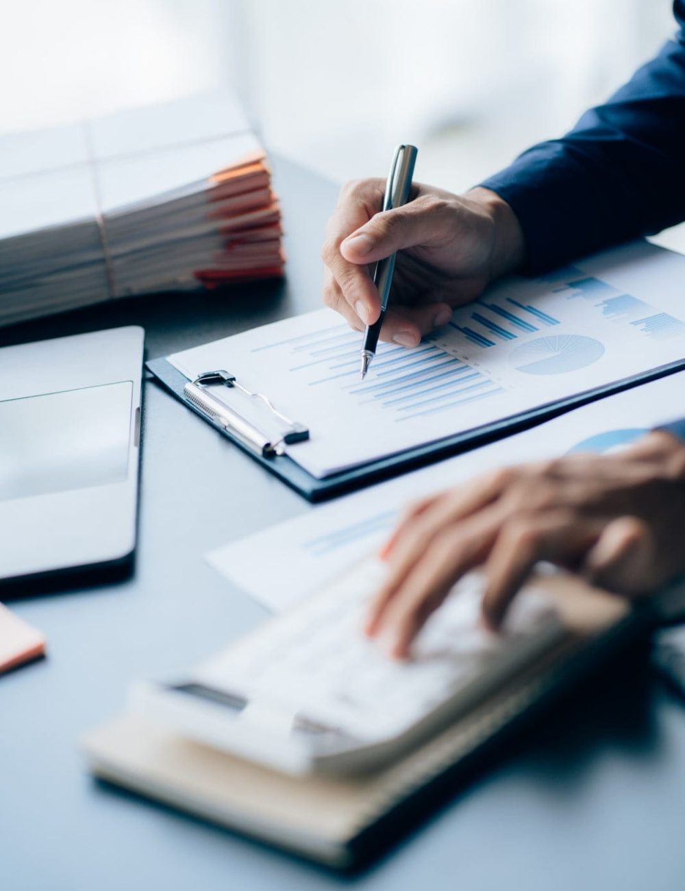 The hands of a male businessman are analyzing and calculating the annual income and expenses in a financial graph that shows results To summarize balances overall in office